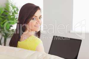 Relaxed girl sitting on a sofa using a laptop