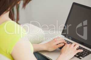 Girl typing on laptop sitting on a sofa