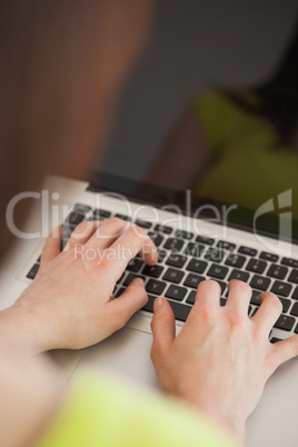 Girl typing on a laptop sitting on a sofa