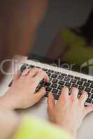 Girl typing on a laptop sitting on a sofa