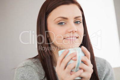 Thoughtful girl holding a cup of coffee and looking at camera