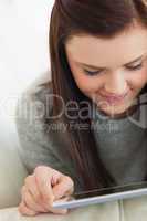 Cheerful girl using a tablet pc on a sofa