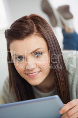 Smiling girl looking at camera using a tablet pc on a sofa