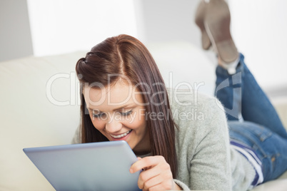 Relaxed girl looking and using a tablet pc on a sofa