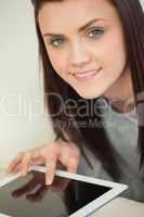 Smiling pretty girl using a tablet pc on a sofa looking at camer