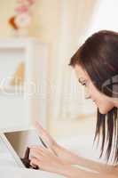 Pretty young girl using a tablet pc lying on her bed