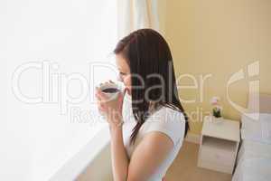 Girl drinking a cup of coffee in a bedroom