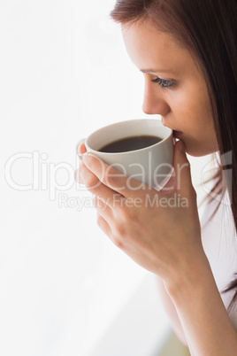 Thoughtful teen holding a cup of coffee looking away