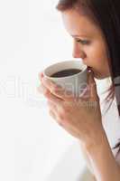 Thoughtful teen holding a cup of coffee looking away