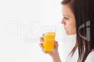 Thoughtful girl holding a glass of orange juice and looking away