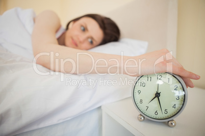 Awakened girl turning off her alarm clock