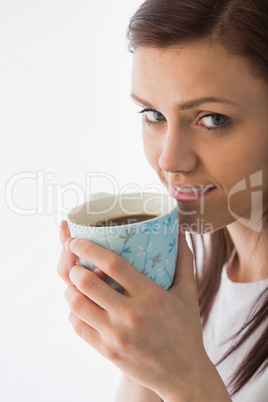 Thoughtful girl looking at camera and drinking a cup of coffee