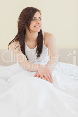 Awakened girl looking away and sitting in her bed