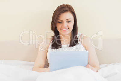 Smiling girl using a tablet pc lying on a bed