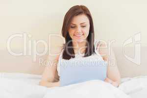 Smiling girl using a tablet pc lying on a bed