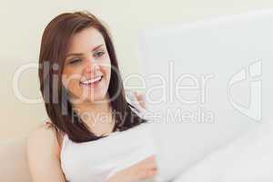 Laughing girl looking and using a laptop lying on a bed