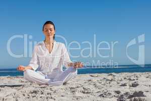 Woman in white doing yoga on the beach