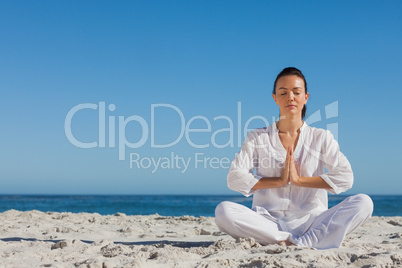 Peaceful woman practicing yoga on the beach