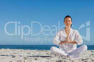 Peaceful woman practicing yoga on the beach