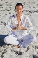 Concentrated woman practicing yoga on the beach
