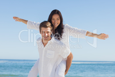 Woman sitting on mans back smiling at camera