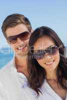 Young couple wearing sunglasses and smiling at camera