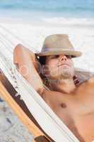 Man wearing straw hat lying in hammock