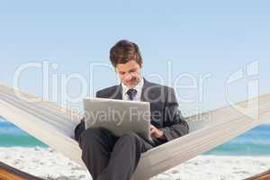 Businessman typing on his laptop in a hammock