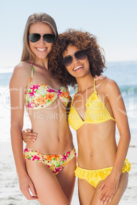 Two pretty friends in bikinis wearing sunglasses posing