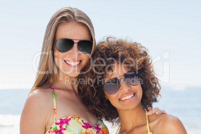 Two friends wearing sunglasses smiling at camera