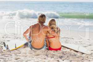 Rear view of a couple sitting on the beach and looking at the se