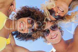 Low angle view of friends on beach wearing sunglasses