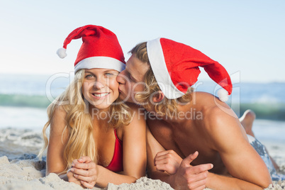 Man giving kiss to partner wearing christmas hats