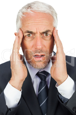 Surprised businessman looking at camera holding his temples