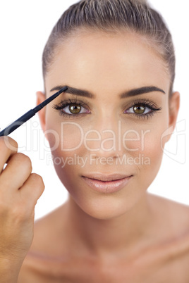 Content woman applying make up on her eyebrows