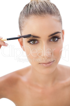 Serious woman applying make up on her eyebrows