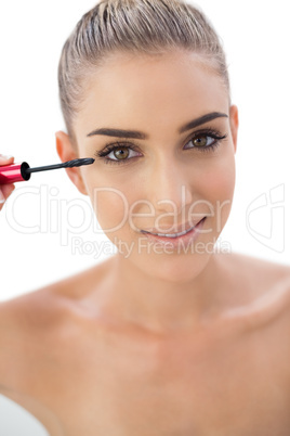 Smiling woman applying mascara