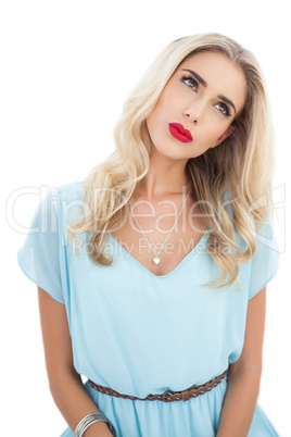 Concentrated blonde model in blue dress looking away