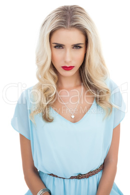 Puzzled blonde model in blue dress looking at camera