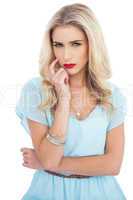Pensive blonde model in blue dress looking at camera