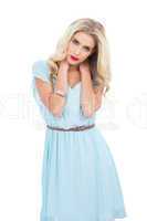 Attractive blonde model in blue dress posing with hands on the h