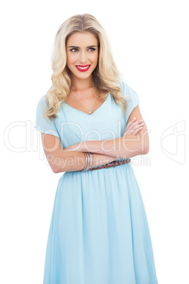 Smiling blonde model in blue dress posing crossed arms