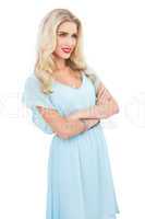 Pleased blonde model in blue dress posing crossed arms