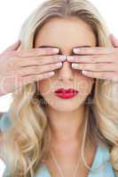 Blonde model in blue dress hidding her eyes with her hands