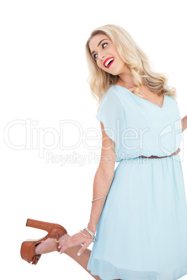 Smiling blonde model in blue dress posing and jumping