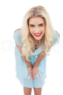 Happy blonde model in blue dress posing hands on the thighs