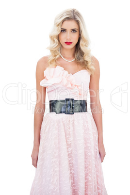 Serious blonde model in pink dress looking at camera