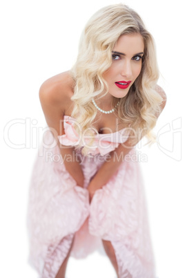 Dreamy blonde model in pink dress posing hands on the thighs