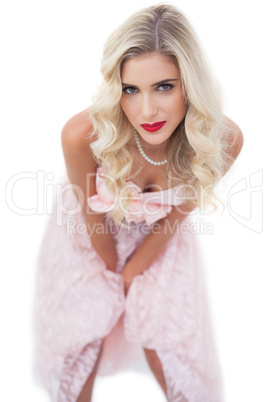 Pretty blonde model in pink dress posing hands on the thighs