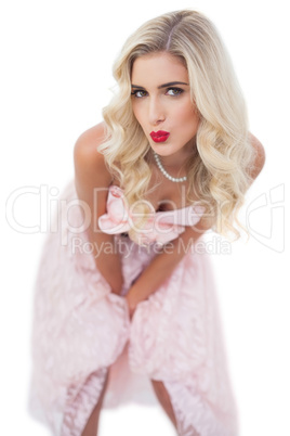 Cute blonde model in pink dress posing hands on the thighs